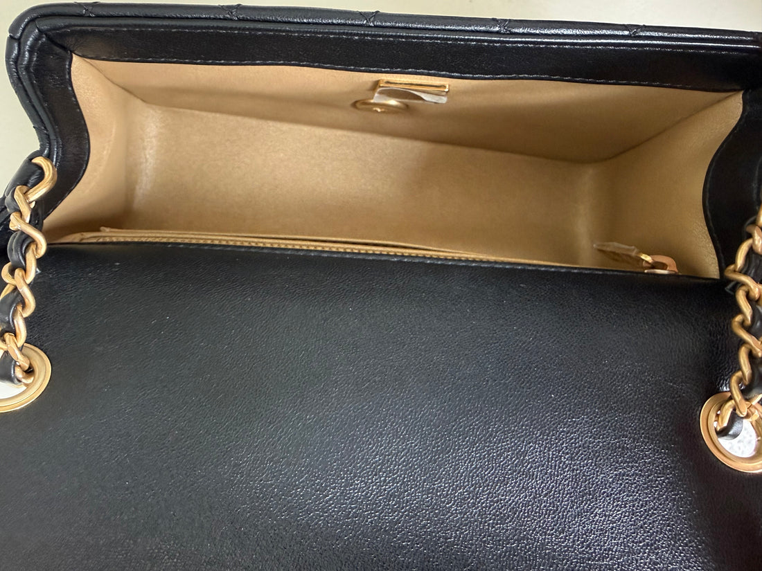 Chanel Pearl Crush Mini Flap Bag ist aus schwarzem Lammleder und zeichnet sich durch goldene Hardware sowie eine verstellbare Kette mit einer ikonischen Perlenkugel aus.