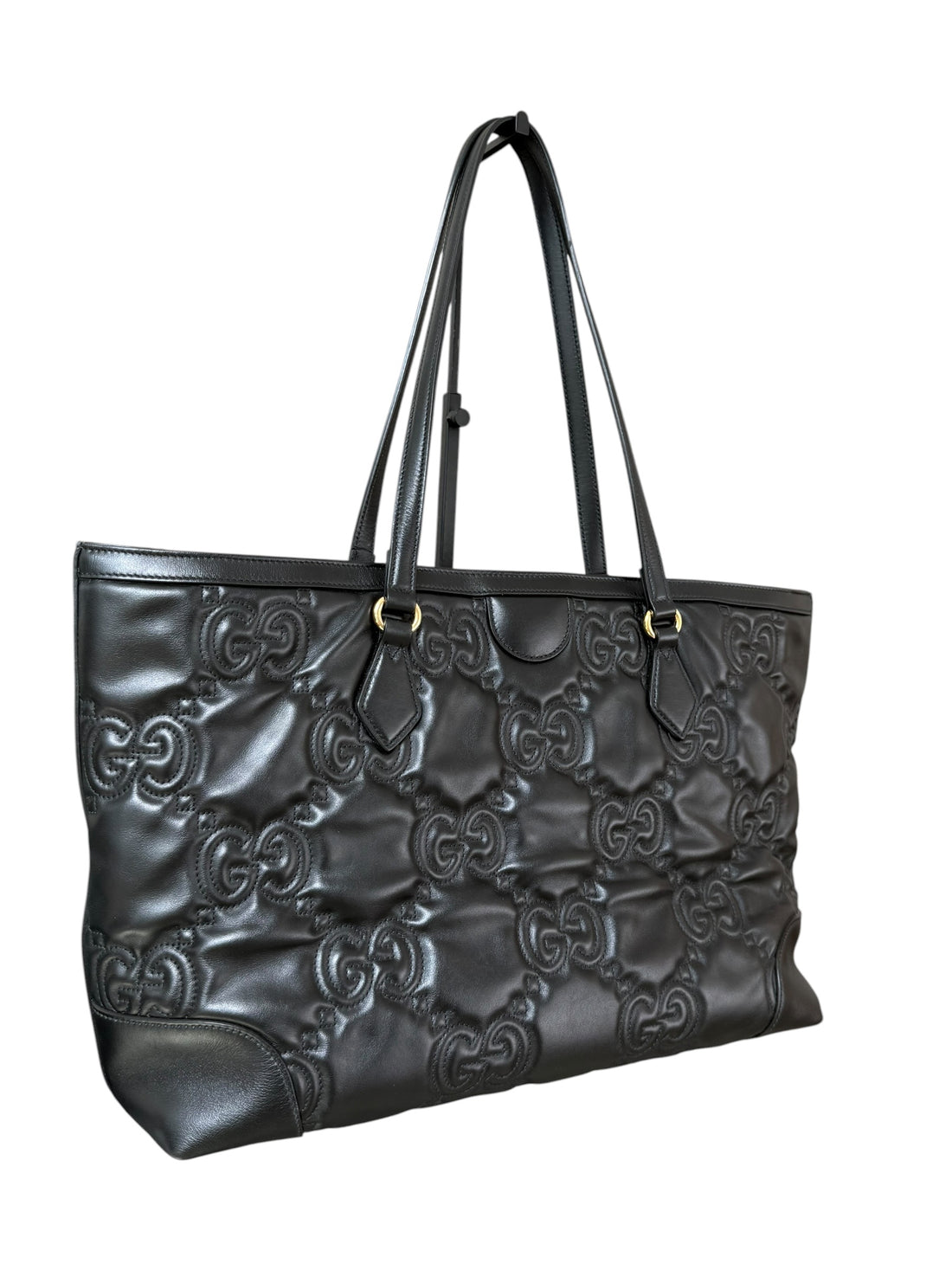 Gucci GG Matelassé Tote Bag aus schwarzem Kalbsleder zeichnet sich durch ihre charakteristische Steppung, das ikonische GG-Muster und glänzende, goldfarbene Logo-Details aus.