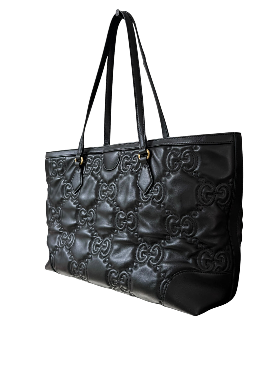 Gucci GG Matelassé Tote Bag aus schwarzem Kalbsleder zeichnet sich durch ihre charakteristische Steppung, das ikonische GG-Muster und glänzende, goldfarbene Logo-Details aus.