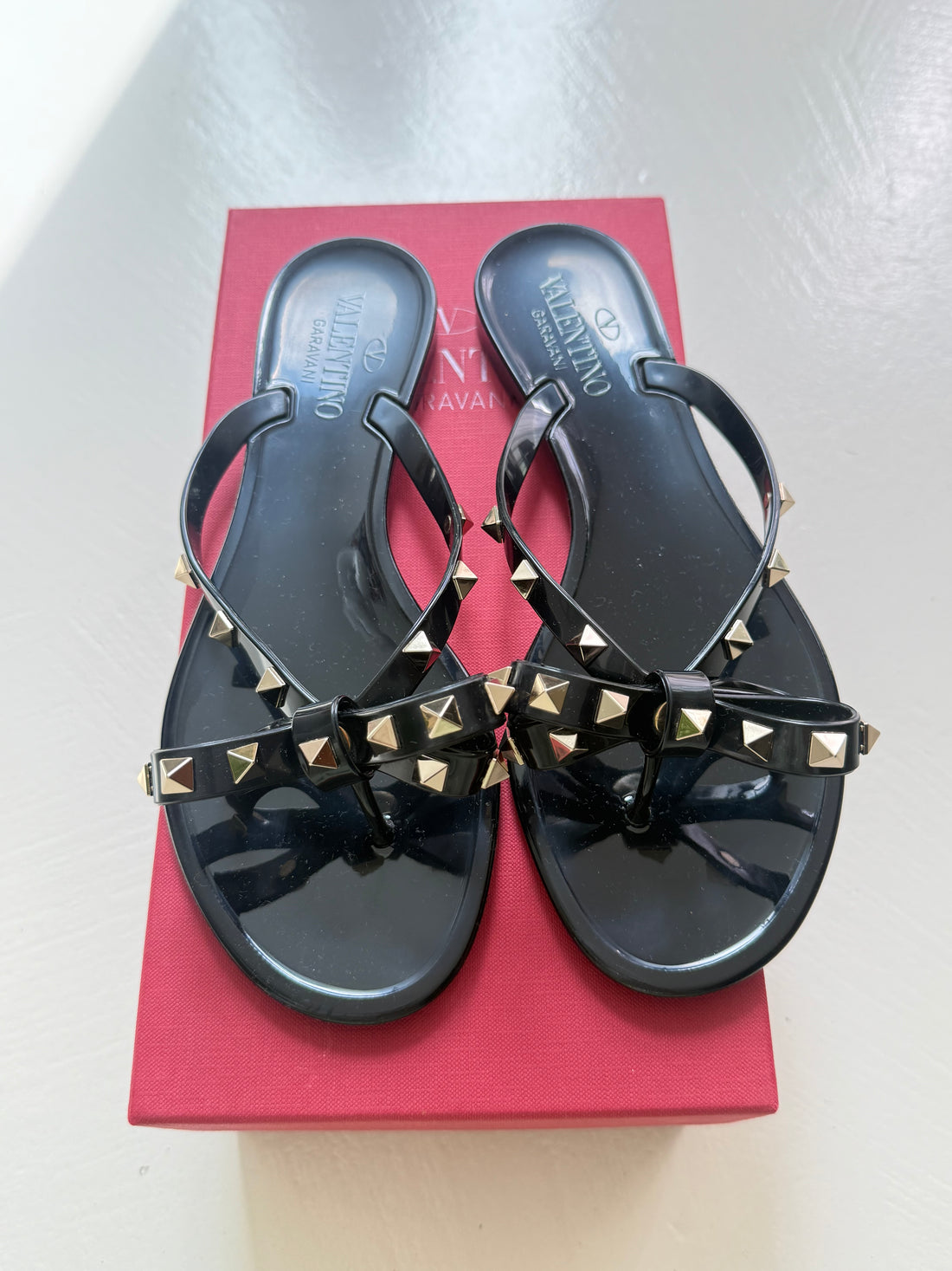 Valentino Garavani Rockstud Slipper aus Gummi in Schwarz mit goldfarbenen Nieten und Schleifendetails.