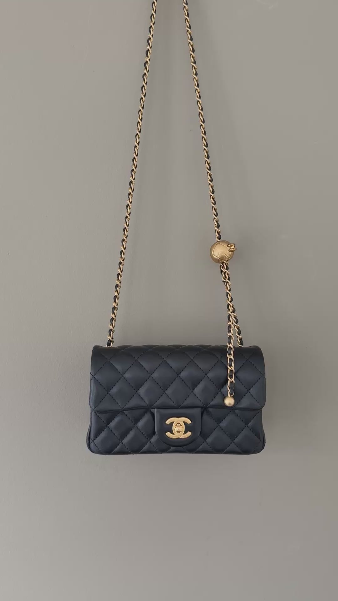 Chanel Pearl Crush Mini Flap Bag ist aus schwarzem Lammleder und zeichnet sich durch goldene Hardware sowie eine verstellbare Kette mit einer ikonischen Perlenkugel aus.