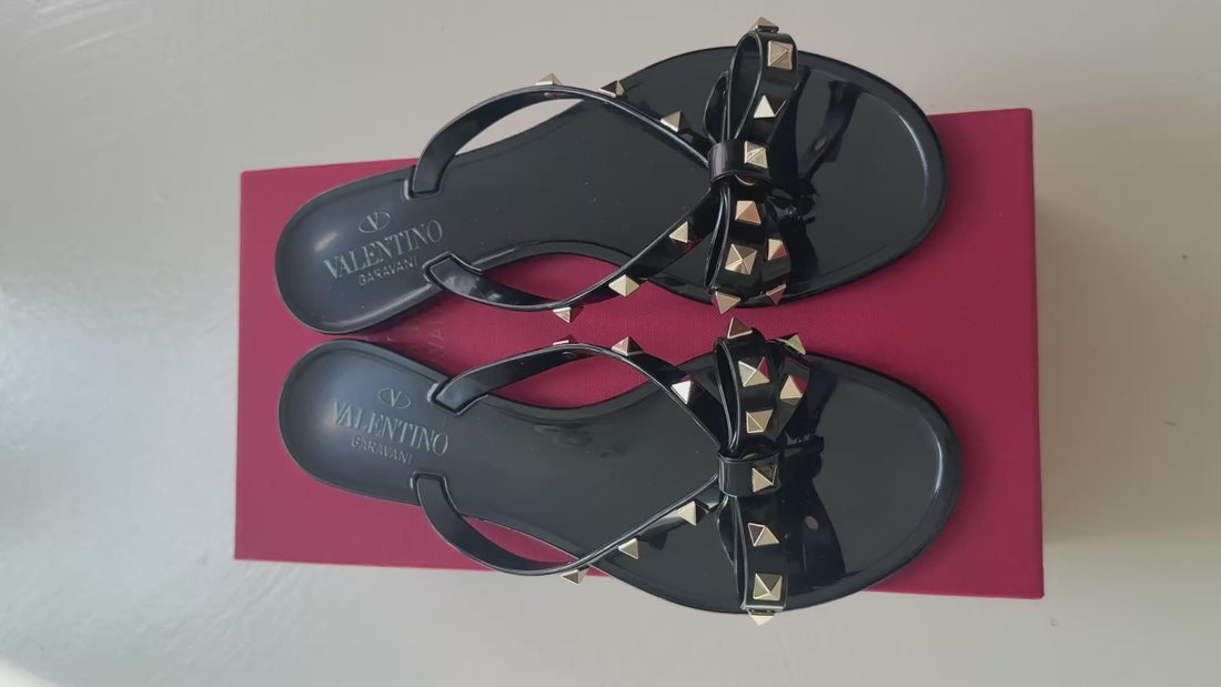 Valentino Garavani Rockstud Slipper aus Gummi in Schwarz mit goldfarbenen Nieten und Schleifendetails.